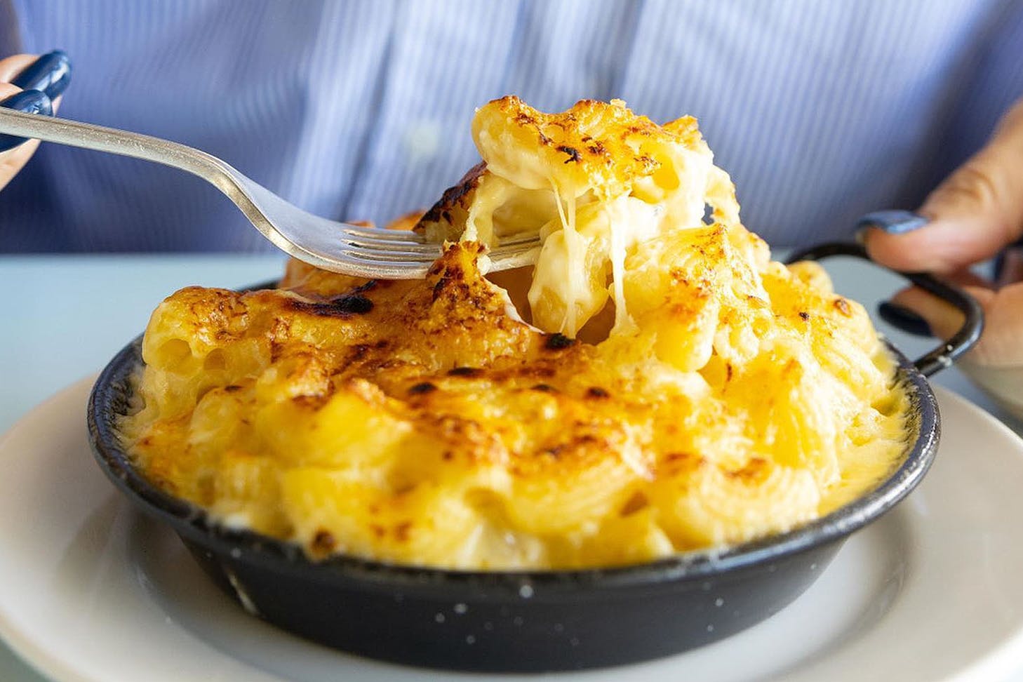 A person tucks into the legendary Mac N Cheese at The Oyster Inn on Waiheke Island.